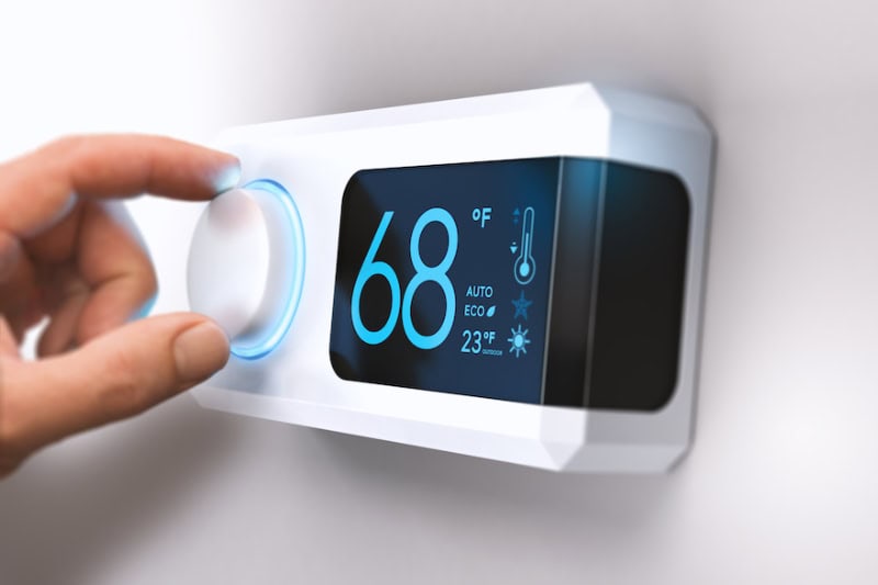 Hand adjusting thermostat temperature in Vernon, British Columbia, home.