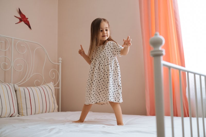Young Canadian girl dancing on bed, enjoying the fresh indoor air quality.