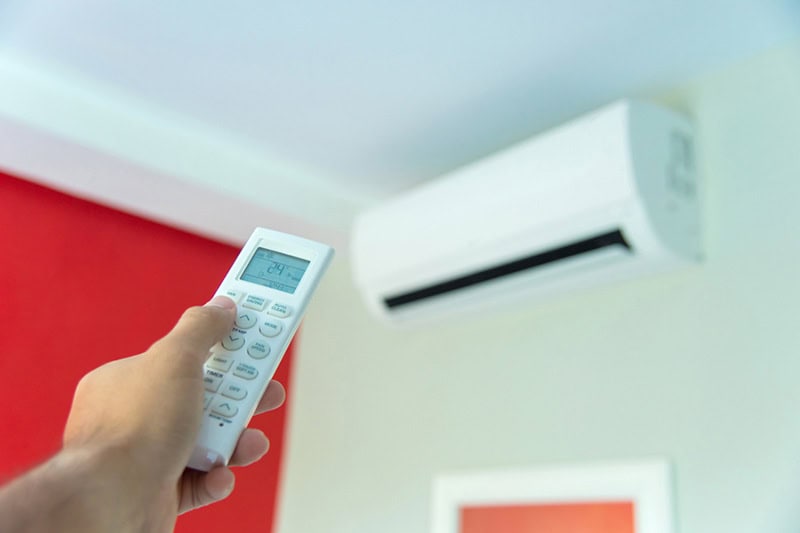 Man holding control to a ductless mini split in his Vernon, BC, home.