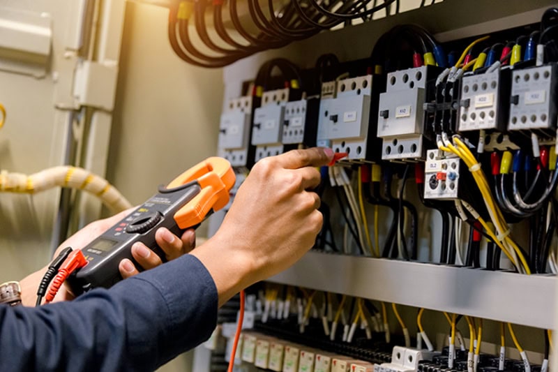 Electrical System Maintenance Can Save Your Health and Home. An electrician working on a panel.