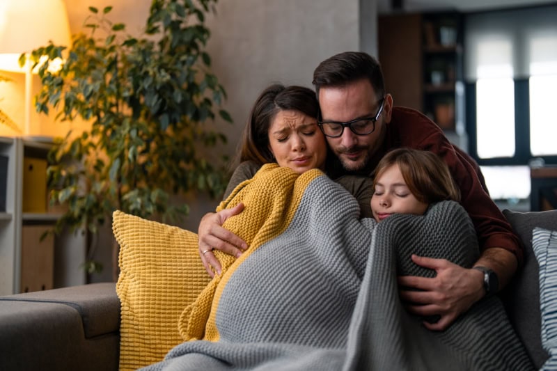 Why Isn’t My Furnace Heating My Entire Home? Family of three freezing in their home, huddled under a blanket to keep warm.