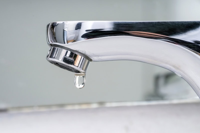 What Problems Can a Leaky Faucet Cause? Photo of a bathroom faucet leaking water.